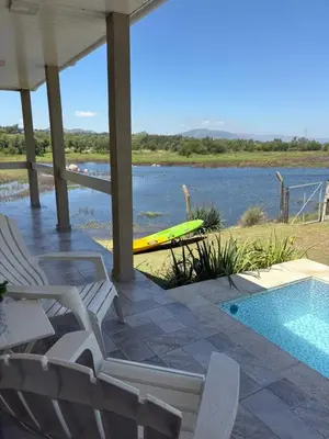 a pool with chairs and a kayak next to the water at Cabañas Titina's Lake in Potrero de Garay