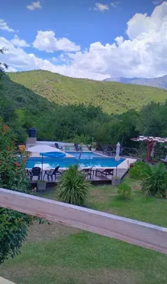 a swimming pool with tables and chairs and a hill at Complejo Mirador de las Sierras pileta climatizada al aire libre in San Javier