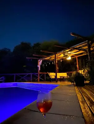 a wine glass sitting next to a pool at night at Complejo Mirador de las Sierras pileta climatizada al aire libre in San Javier