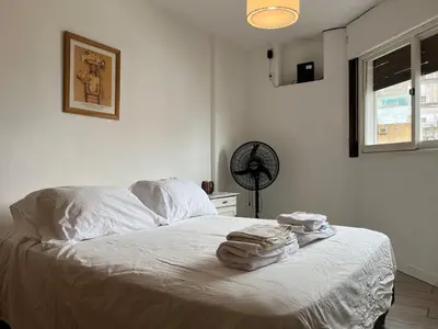 a bedroom with a bed with white sheets and a fan at Hermoso departamento en el centro de Cordoba, somos ApartamentosCordoba in Cordoba