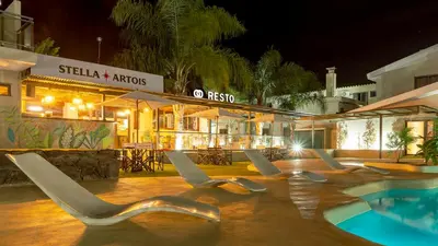 a group of chairs next to a swimming pool at night at Wooden Hotel in Villa Carlos Paz