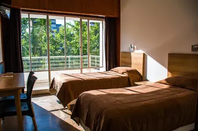 a hotel room with two beds and a window at Grand Hotel Rio Cuarto in Río Cuarto