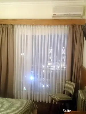 a bedroom with a window with curtains and a chair at Grand Hotel Rio Cuarto in Río Cuarto