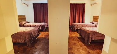 a room with three beds with red curtains at Grand Hotel Rio Cuarto in Río Cuarto