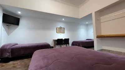 a bedroom with two beds and a flat screen tv at Grand Hotel Rio Cuarto in Río Cuarto