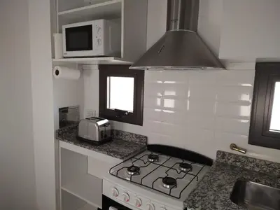 a kitchen with a stove and a microwave at Aparts Kodu- Residencia Familiar in Río Cuarto