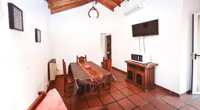 a dining room with a table and a tv on a wall at La Candida departamentos in Merlo