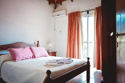 a bedroom with a bed with pink pillows and a window at La Candida departamentos in Merlo