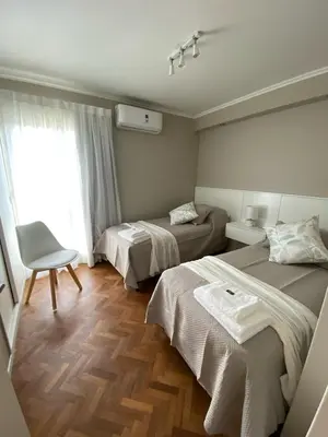 a hotel room with two beds and a chair at DEPARTAMENTO CENTRICO CON COCHERA - CORDOBA Argentina- in Cordoba