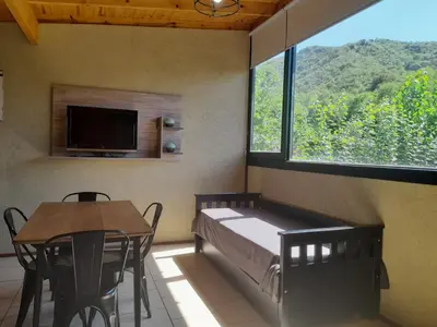 a bedroom with a bed and a table and a window at Balcón de la montaña in Santa Rosa de Calamuchita