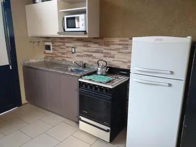 a kitchen with a stove and a white refrigerator at Balcón de la montaña in Santa Rosa de Calamuchita