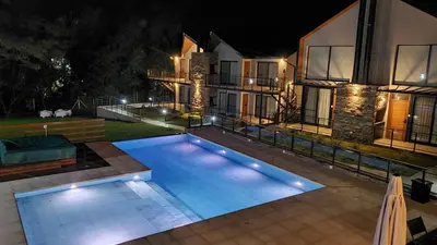 a swimming pool in front of a house at night at El Nogal Apart Hotel in Villa General Belgrano