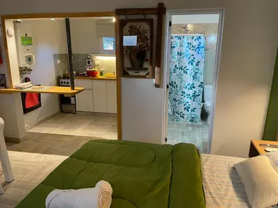 a living room with a green couch and a kitchen at CasitaLiu in Villa General Belgrano