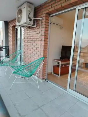 a balcony with a table and chairs and a tv at Departamento Boho Chic Corazón de Nueva Córdoba in Cordoba