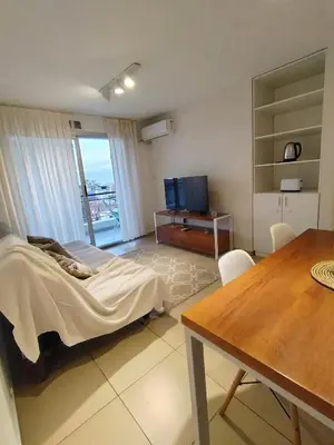 a room with a bed and a table and a television at Departamento Boho Chic Corazón de Nueva Córdoba in Cordoba