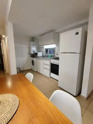 a kitchen with a table and a white refrigerator at Departamento Boho Chic Corazón de Nueva Córdoba in Cordoba