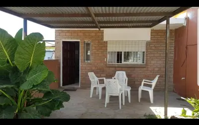 a patio with white chairs and a table and a brick wall at Lo de Liliana in Tanti
