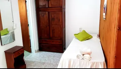 a bedroom with a bed with a green pillow and towels at Lo de Liliana in Tanti