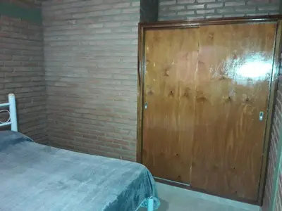 a bedroom with a wooden door and a brick wall at Cabañas Don Pocho in Villa Cura Brochero
