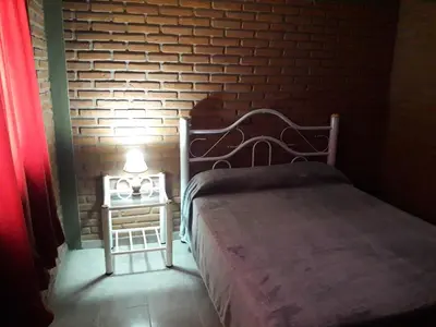 a bedroom with a bed and a brick wall at Cabañas Don Pocho in Villa Cura Brochero