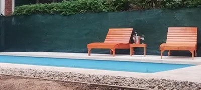 two chairs and a table next to a pool at Cabañas Don Pocho in Villa Cura Brochero