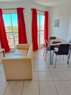 a living room with a couch and a table and red curtains at ALTOS DE CLERMONT in Cordoba