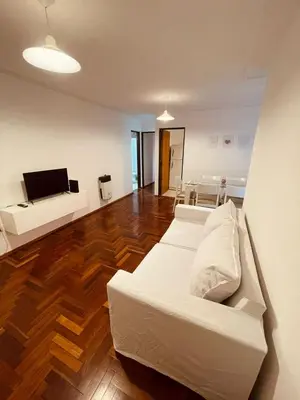 a living room with a white couch and a wooden floor at LitStay - Departamento con Cochera Barrio General Paz in Cordoba