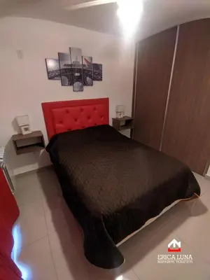 a bedroom with a bed with a red head board at Departamento centrico Carlos Paz in Villa Carlos Paz