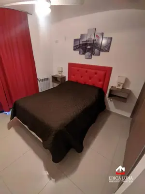 a bedroom with a red bed and red curtains at Departamento centrico Carlos Paz in Villa Carlos Paz