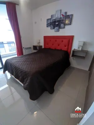 a bedroom with a bed with a red head board at Departamento centrico Carlos Paz in Villa Carlos Paz