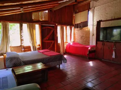 a bedroom with a bed and a tv and a couch at Pachamama cabañas en la montaña in Mina Clavero