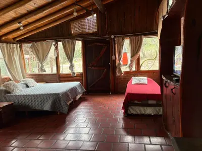 a room with two beds and a tv in it at Pachamama cabañas en la montaña in Mina Clavero