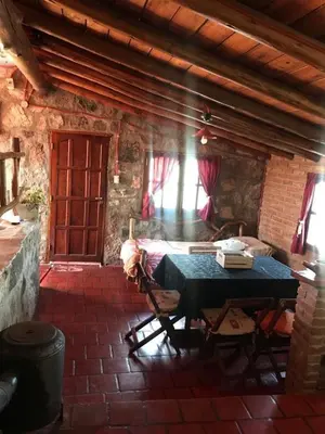 a room with a table and a bed in a building at Pachamama cabañas en la montaña in Mina Clavero