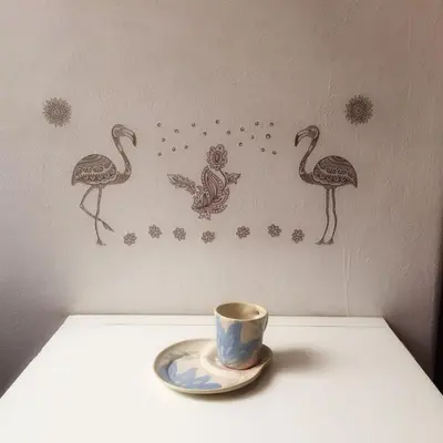 a cup and saucer on a table with birds on the wall at Plazoleta Apartamento in Cordoba