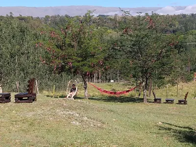 a person sitting in a hammock in a field at ALA DE LIBERTAD in Villa Yacanto
