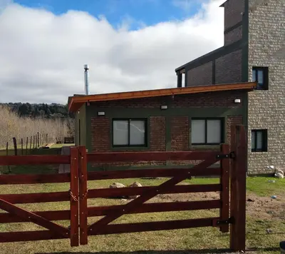 a house with a wooden fence in front of it at ALA DE LIBERTAD in Villa Yacanto
