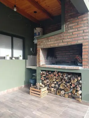 a stack of logs in a room with a brick wall at ALA DE LIBERTAD in Villa Yacanto