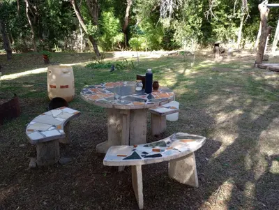 a picnic table and two benches in a park at Casa Del Valle Traslasierra in Las Chacras (La Paz)