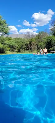 a group of people swimming in a body of water at Casa Del Valle Traslasierra in Las Chacras (La Paz)