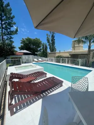 a swimming pool with two lounge chairs and an umbrella at Brisas del Sur in Villa Carlos Paz