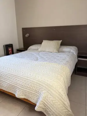 a large white bed with a wooden head board at Brisas del Sur in Villa Carlos Paz