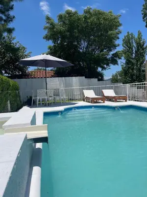 a swimming pool with an umbrella and chairs and a table at Brisas del Sur in Villa Carlos Paz