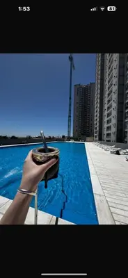 a hand holding a cell phone next to a swimming pool at A estrenar!Moderno, Nordic Nest in Cordoba