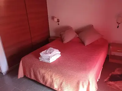a bedroom with a bed with red sheets and pink pillows at Cabañas del Cerro Mirador in Villa Rumipal