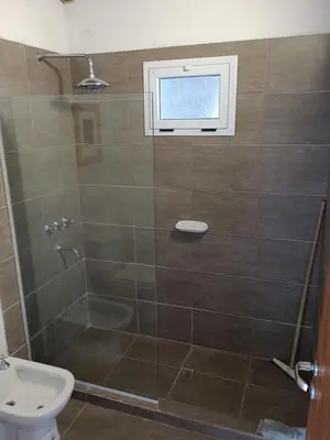 a bathroom with a shower with a toilet and a window at Cabañas del Cerro Mirador in Villa Rumipal