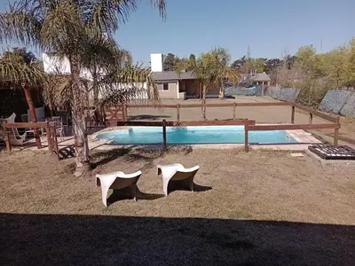 a swimming pool with two white chairs in the yard at Cabañas del Cerro Mirador in Villa Rumipal
