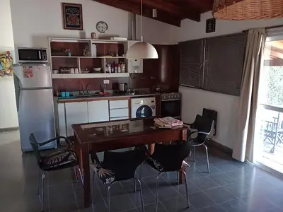 a kitchen with a table and chairs and a refrigerator at Cabañas del Cerro Mirador in Villa Rumipal