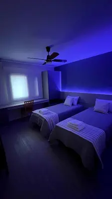 two beds in a room with a purple lighting at Verona in Cordoba