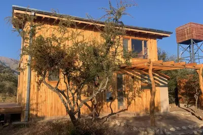 a wooden house with a tree in front of it at Mandala Tiny House, Traslasierra. in Yacanto