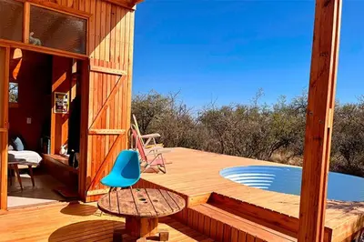 a wooden deck with a table and a blue chair at Mandala Tiny House, Traslasierra. in Yacanto